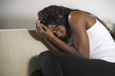 genç çekici ve üzgün oturan siyah Afrikalı-Amerikalı kadın evde kanepe depresif duygu endişeli ve sinirli depresyon sorunu ve anksiyete krizi çaresiz ağlama acı kanepe