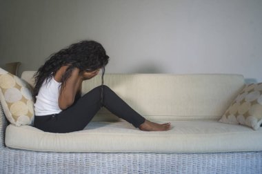 genç çekici ve üzgün oturan siyah Afrikalı-Amerikalı kadın evde kanepe depresif duygu endişeli ve sinirli depresyon sorunu ve anksiyete krizi çaresiz ağlama acı kanepe