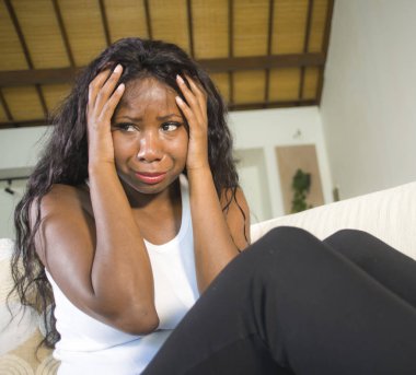 genç çekici ve üzgün oturan siyah Afrikalı-Amerikalı kadın evde kanepe depresif duygu endişeli ve sinirli depresyon sorunu ve anksiyete krizi çaresiz ağlama acı kanepe