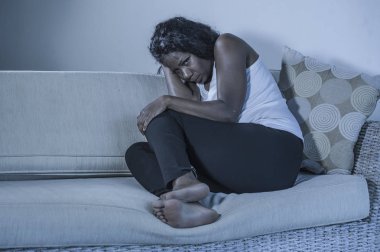 genç çekici ve üzgün oturan siyah Afrikalı-Amerikalı kadın evde kanepe depresif duygu endişeli ve umutsuz sorun depresyon ve anksiyete krizi ya da kırık kalp acı kanepe
