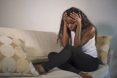 genç çekici ve üzgün oturan siyah Afrikalı-Amerikalı kadın evde kanepe depresif duygu endişeli ve sinirli sorun depresyon ve anksiyete krizi ya da korkunç baş ağrısı acı kanepe