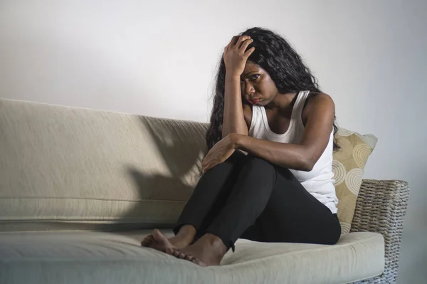 年轻的迷人和可悲的黑人非洲裔美国妇女坐在沮丧的家庭沙发沙发上感到焦虑和沮丧遭受抑郁症的问题和焦虑危机或可怕的头痛 — 图库照片