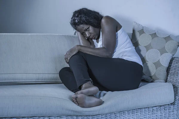 genç çekici ve üzgün oturan siyah Afrikalı-Amerikalı kadın evde kanepe depresif duygu endişeli ve umutsuz sorun depresyon ve anksiyete krizi ya da kırık kalp acı kanepe