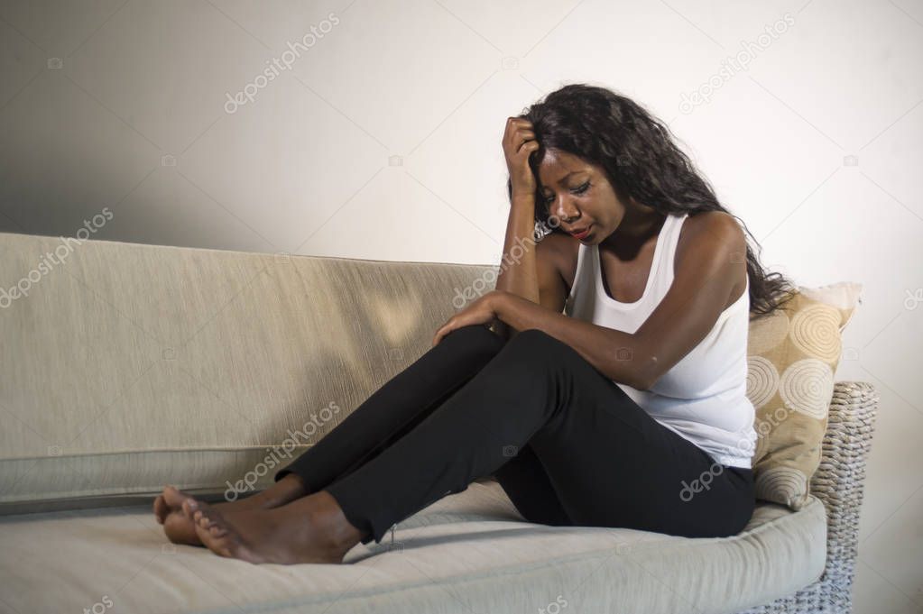 young attractive and sad black African American woman sitting depressed at home sofa couch feeling anxious and frustrated suffering depression problem and anxiety crisis or terrible headache