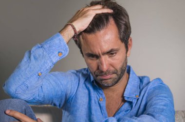 genç çekici ve yakışıklı yaşam tarzı portre üzgün oturan latin adam yorgun ve evde depresif duygu koltuk kanepe boğulmuş ve depresyon anksiyete ve kriz sorun acı endişeli