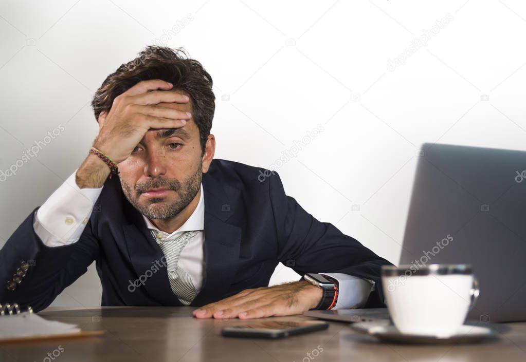 young desperate and stressed businessman feeling depressed and overwhelmed working at office computer desk tired and exhausted  defeated by business financial crisis problem