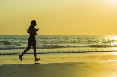 koşu ve günbatımı sağlık ve açık havada faaliyet zevk güzel Plajı'nda çalışan fitness egzersiz egzersiz genç mutlu ve çekici Afro-Amerikan atlet kadın silüeti 