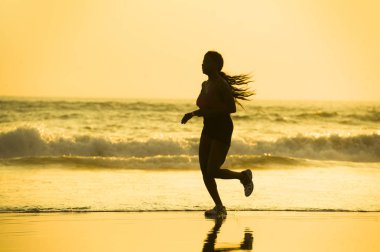 koşu ve günbatımı sağlık ve açık havada faaliyet zevk güzel Plajı'nda çalışan fitness egzersiz egzersiz genç mutlu ve çekici Afro-Amerikan atlet kadın silüeti 