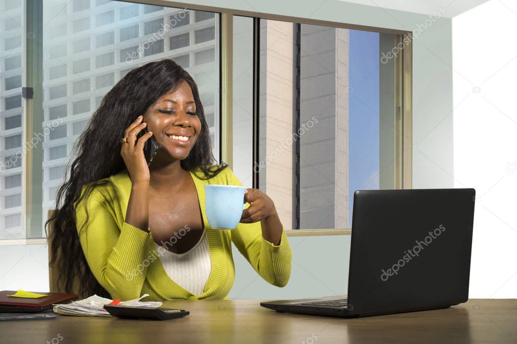 office corporate portrait of young happy and attractive black African American businesswoman working confident at computer desk talking on mobile phone satisfied in financial business success