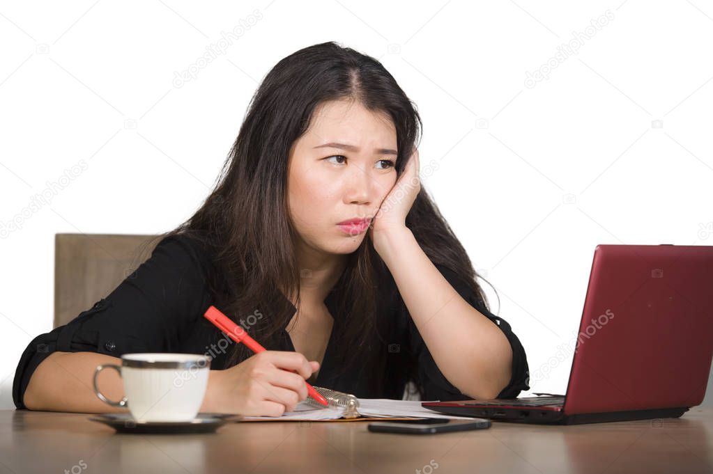 young beautiful sad and depressed Asian Chinese business woman working in stress at office computer desk feeling overwhelmed and frustrated suffering headache and depression isolated