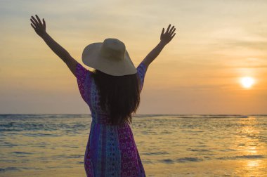 Yaz şapka güneşe denizin üzerinde inanılmaz güzel gün batımı sırasında tropik cennet plaj tatil arayan genç mutlu ve rahat kadın özgürlük kavramı Yayilim kollarında seyahat