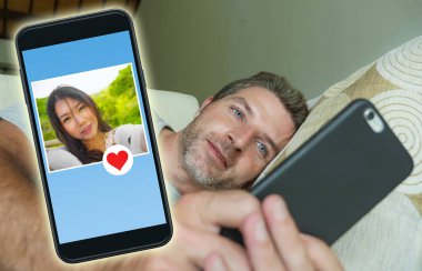 Genç yakışıklı ve mutlu bir adam aşk flört ve flört online gibi güzel Çinli Asyalı teknoloji romantizm kavramı gönderme arama cep telefonunda internet sosyal medya kullanarak