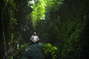 pratik yoga sağlık kavramı içinde gevşeme ve meditasyon egzersiz yaparak rock oturan açık havada etkileyici huzurlu ve taze tropikal bir geçmiş, genç güzel ve mutlu Asya