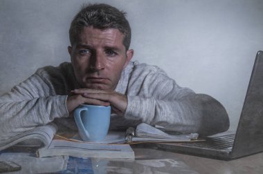 Genç endişeli ve sinirli ve yorgun muhasebe evrakları duygu ya sınav için eğitim dizüstü bilgisayar masası grunge arka plan üzerinde izole gece yarısı evde çalışan erkeğin depresif