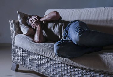 evde düşük yatan genç umutsuz üzgün ve sinirli adam depresyon sorunu ve anksiyete krizi ağlıyor çaresiz ağrı hissi hasta ve hasta üzerinde dramatik ışık acı koltuk kanepe
