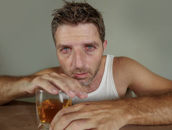 Молодой пьяный и подавленный алкоголик, сидящий в грязном стакане виски, испытывающий отчаянные проблемы с алкоголизмом и алкогольной зависимостью в алкогольной концепции
