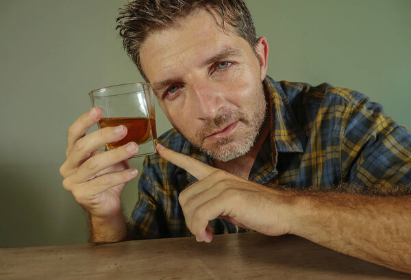 young drunk addict and alcoholic man drinking whiskey glass intoxicated and wasted smiling stupid on isolated background in alcohol addiction booze abuse and alcoholism problem