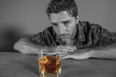 isolated black and white portrait of young messy depressed alcoholic man having a drink looking at whiskey glass feeling temptation of alcohol abuse in addiction and alcoholism problem clipart