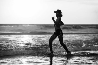 Silhouette uyum ve atletik Asyalı Çinli sportif kadın fitness sağlıklı yaşam tarzı ve yaz açık havada etkinlik kavramı Sunset'teki koşu egzersiz yapıyor güzel plaj üzerinde çalışan