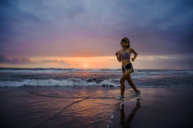 Silhouette uyum ve atletik Asyalı Çinli sportif kadın fitness sağlıklı yaşam tarzı ve yaz açık havada etkinlik kavramı Sunset'teki koşu egzersiz yapıyor güzel plaj üzerinde çalışan