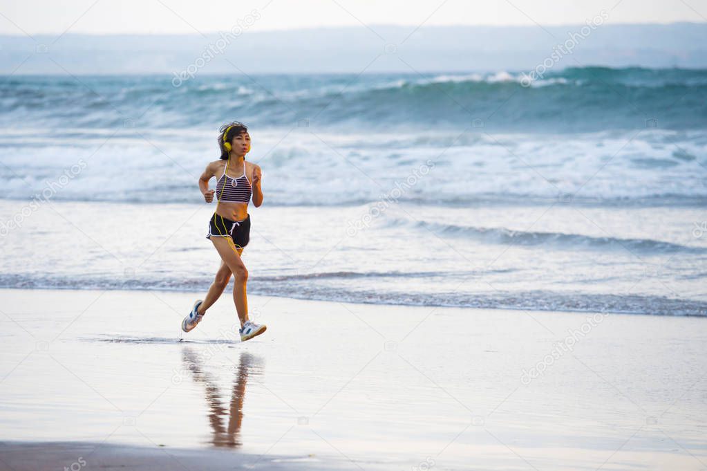 fit and athletic Asian Chinese sporty woman running on beautiful beach doing jogging workout on sunset in fitness healthy lifestyle and summer outdoors activity concept