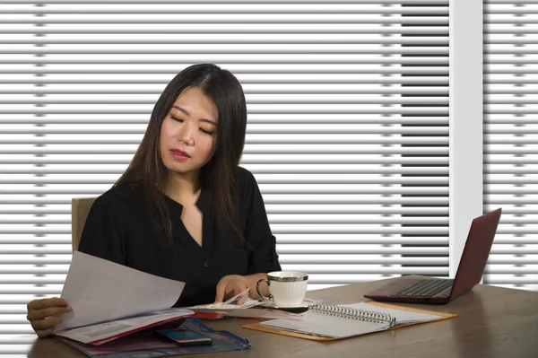 company corporate portrait of young beautiful and busy Asian Chinese woman working busy at modern office computer desk by venetian blinds window in business lifestyle and executive job concept