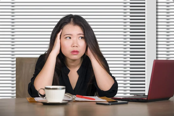corporate portrait of young attractive sad and stressed Asian Chinese woman working at company office computer desk feeling depressed and overwhelmed in business lifestyle and job  problem