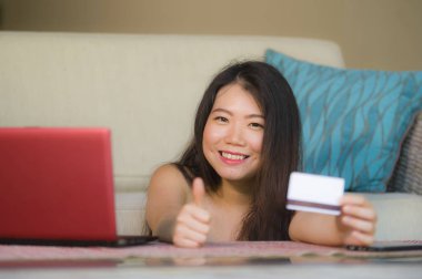 internet iş ve e.commerce kavramında genç güzel yaşam tarzı portresi ve kredi kartı bankacılık ve online alışveriş dizüstü bilgisayar ile evde tutan mutlu Asyalı Çinli kadın kanepe