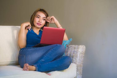 oturma odası kredi kartı bankacılık ve online alışveriş gülümseyen için dizüstü bilgisayar kullanan holding'e-ticaret ve internet ticaret rahat genç güzel ve mutlu bir kız evde yaşam tarzı portresi 
