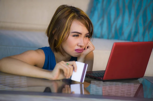 Retrato de estilo de vida de jovem atraente e chateado mulher em casa sofá verificando finanças com cartão de crédito e computador portátil preocupado e estressado sofrendo problema de dinheiro — Fotografia de Stock