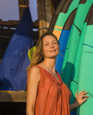 Genç güzel baş ve omuzlar portresi ve sörf güzellik moda yaz konsepti içinde eğilerek renkli surf kurulları ile rahat ve neşeli poz gülümseyen mutlu sarışın kadın