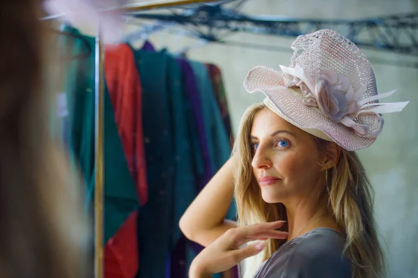 young beautiful and happy woman enjoying shopping trying out clothes and vintage hat looking at mirror in beauty fashion store smiling cheerful having fun buying sales and opportunity clothing