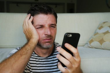 cep telefonu yorgun ve mutsuz sinirli yüz ifadesinde evde kullanan genç çekici ve stresli adam portresi yüz kadar oturma odasında internet kapatın ve sosyal medya kavramı bağımlısı