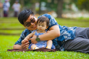sevgi dolu baba ile tatlı ve güzel bebek kız kızı birlikte ebeveynlik sorumluluğu ve sevgi kavramı Park'ta şehir çimenlerin üzerinde oynama oturan zevk olarak mutlu ve eğlenceli Asyalı Çinli adam