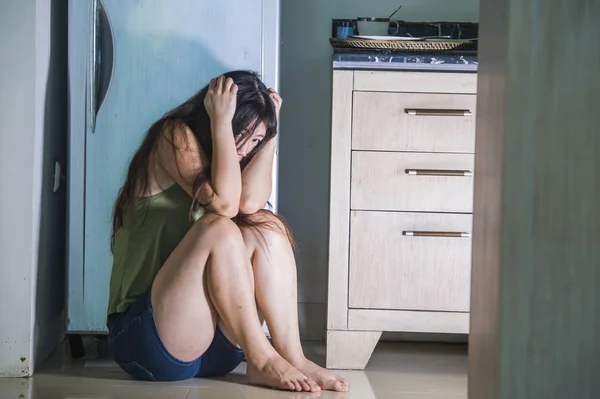 日本の若い怖いと絶望的なアジア女性泣いて苦しんでいる家庭内暴力と嫉妬と酔ってアルコール中毒の夫の性的虐待の被害者家庭の台所床で無力 — ストック写真