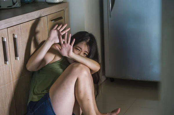 日本の若い怖いと絶望的なアジア女性泣いて苦しんでいる家庭内暴力と嫉妬と酔ってアルコール中毒の夫の性的虐待の被害者家庭の台所床で無力 — ストック写真