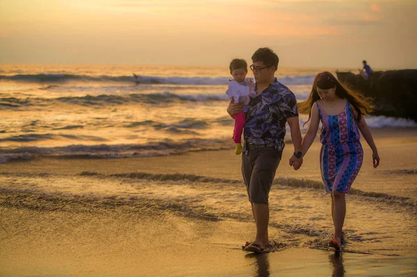 年轻快乐美丽的亚洲一对中国夫妇抱着女婴女儿走在日落海滩享受一起浪漫的暑假旅行在家庭甜蜜假期的概念 — 图库照片