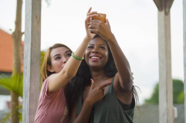 tatil tropikal resort adlı selfie cep telefonu ile birlikte kadınlarda yarış arkadaşlık çekim Asyalı kız arkadaşı ile genç mutlu ve güzel siyah afro Amerikalı kadının