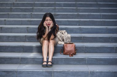 stres ve depresyon kriz mobbing kurbanı olmak acı sokak merdiven üzerinde tek başına oturmuş ağlıyor ya da işini kaybetmek ateş genç depresif ve umutsuz Asya Amerikan iş kadını