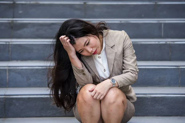 若い落ち込んでいると絶望的なアジア系アメリカ人実業家だけでいじめの犠牲者であるストレスとうつ病の危機に苦しんでいる通りの階段に座って泣いている または彼女の仕事を失うことを解雇 — ストック写真