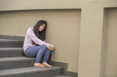 Genç üzgün ve depresyonda Asyalı Çinli öğrenci veya okulda genç sokak merdiven bunalmış ve endişeli çaresiz hissediyor açık havada oturup depresyon sorun acı 