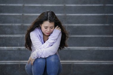 Genç üzgün ve depresyonda Asya Kore öğrenci veya okulda genç sokak merdiven bunalmış ve endişeli çaresiz hissediyor açık havada oturup depresyon sorun acı 