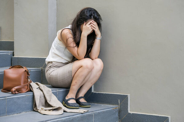 young depressed and desperate businesswoman crying alone sitting on street staircase suffering stress and depression crisis being victim of mobbing or fired losing her job feeling overwhelmed
