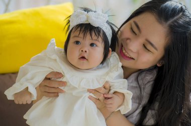 oynama ve tatlı bebek kız yaz tatil gezisi, anne ve küçük kızı sevgi kavramı zevk tatil resort adlı oturan genç mutlu ve sevimli Asyalı Koreli kadın 