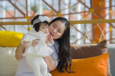 oynama ve tatlı bebek kız yaz tatil gezisi, anne ve küçük kızı sevgi kavramı zevk tatil resort adlı oturan genç mutlu ve sevimli Asyalı Çinli kadın 