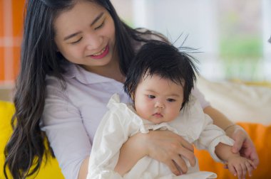 oynama ve tatlı bebek kız yaz tatil gezisi, anne ve küçük kızı sevgi kavramı zevk tatil resort adlı oturan genç mutlu ve sevimli Asyalı Çinli kadın 