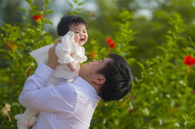 mutlu ve gururlu genç adam kızı bayramlarda çiçek bahçesi önünde tutan küçük bebek kız babası olarak başvurmak zevk birlikte açık havada aile yaşam tarzı kavramı