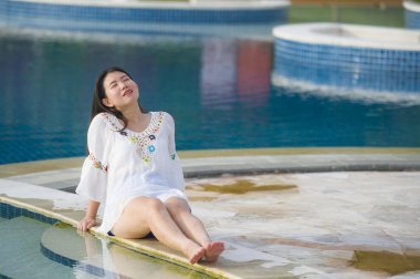 Açık havada Genç mutlu ve güzel Asyalı Çinli turist kadına tropikal resort yüzme havuzu yaz zevk rahatlatıcı yaşam tarzı portresi gülümseyen neşeli rahat hissediyor tatil