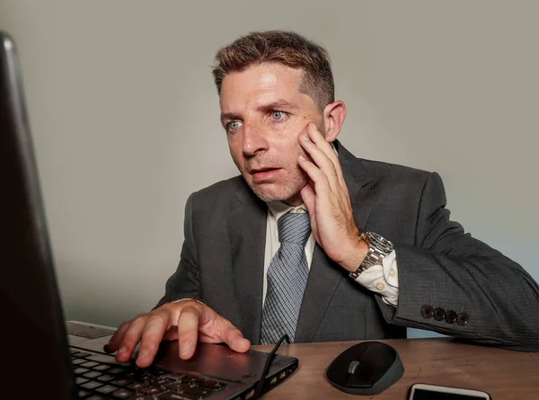 young stressed and overwhelmed businessman in suit and tie working at office laptop computer desk feeling desperate and upset in financial business stress suffering problem at corporate job