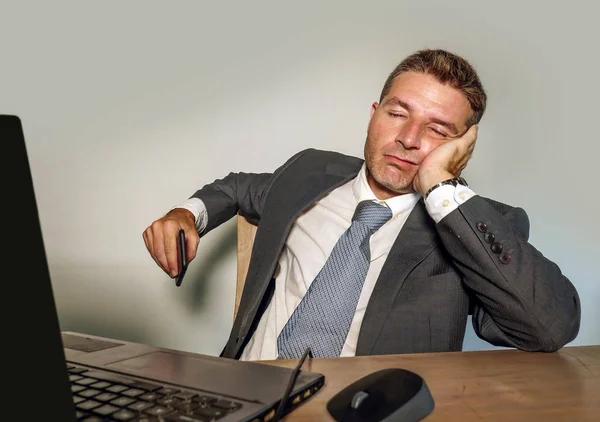 young desperate and depressed business man suffering problem and depression at office desk working with laptop computer feeling frustrated and overwhelmed on isolated background